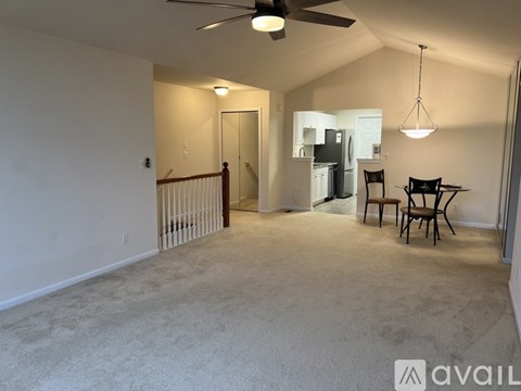 A spacious living room with a ceiling fan and a dining area in the background.