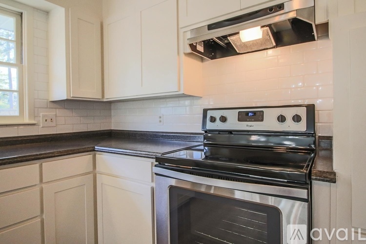 A modern kitchen with a black stove top oven and white cabinets.