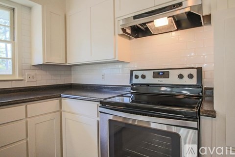 A modern kitchen with a black stove top oven and white cabinets.