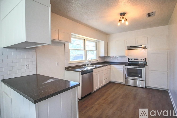 A kitchen with white cabinets and a black countertop.