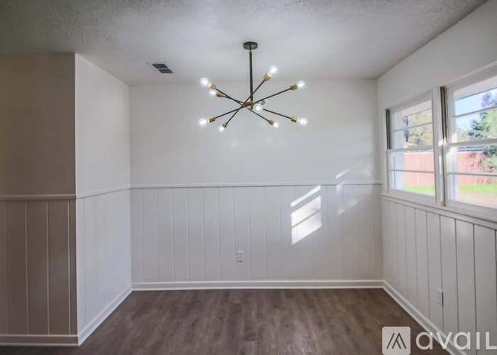 A room with a chandelier and wood flooring.
