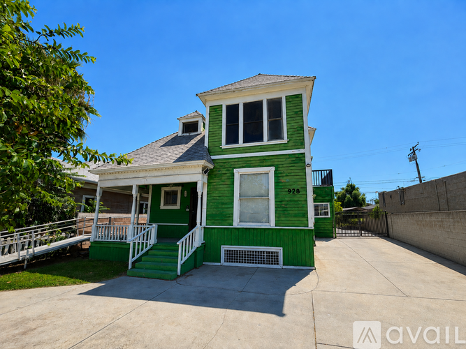 A green house with a white porch and a sign that says "available".