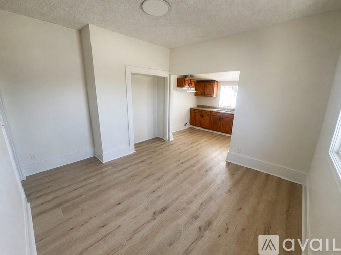 A spacious room with wooden flooring and white walls.