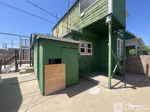 A green building with a wooden door and a window.