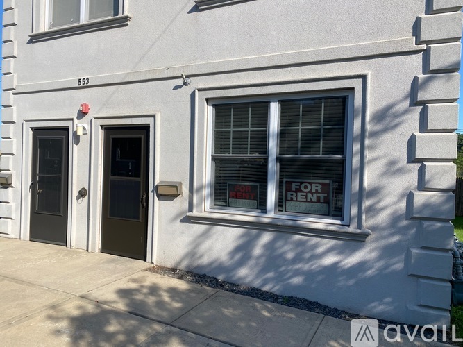 A white building with a black door and a window that is for rent.