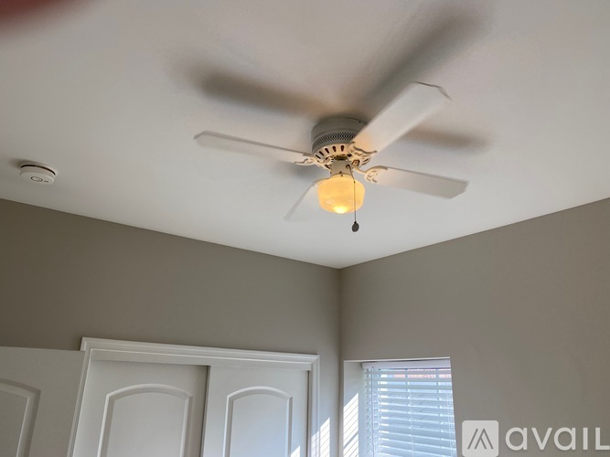 A ceiling fan with a light bulb hanging from it.