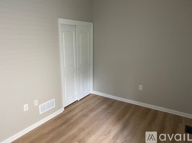 A room with a white door and wooden floor.