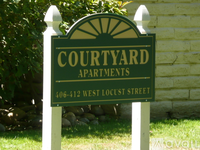 A sign for Courtyard Apartments with a phone number on it.