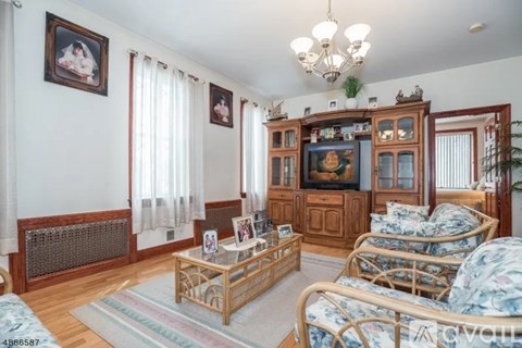 A living room with a wooden cabinet, a sofa, a coffee table, and a chandelier.