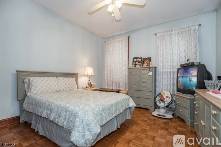 A bedroom with a bed, a dresser, and a television.