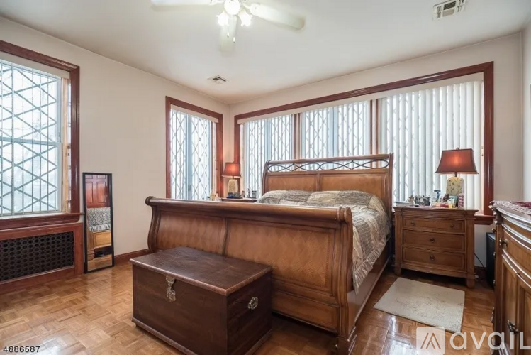 A bedroom with a large bed, wooden furniture, and a ceiling fan.