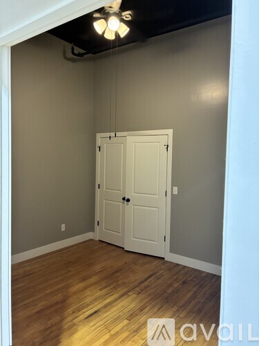 A room with a white door and wooden flooring.