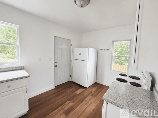 A white kitchen with wood floors and a window.