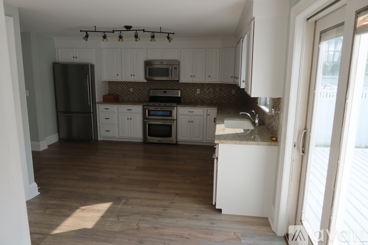 A kitchen with white cabinets and a black fridge.