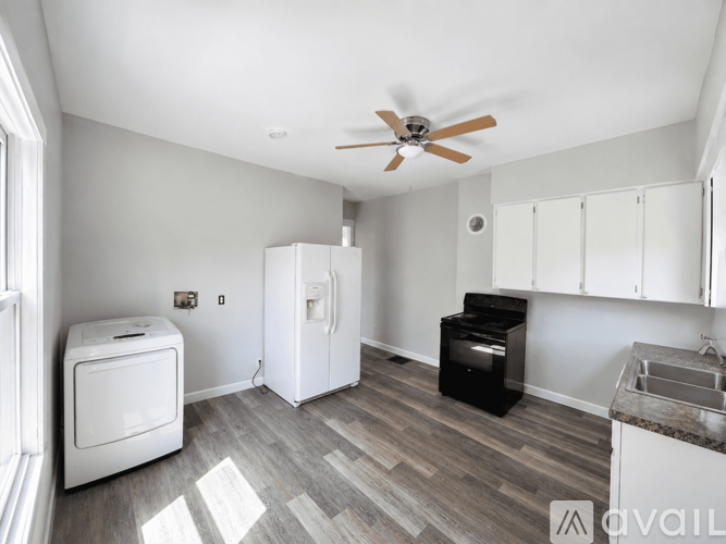 A kitchen with a refrigerator, oven, and a washing machine.