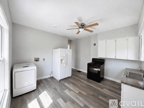 A kitchen with a refrigerator, oven, and a washing machine.