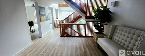 A living room with a white couch and a wooden staircase.