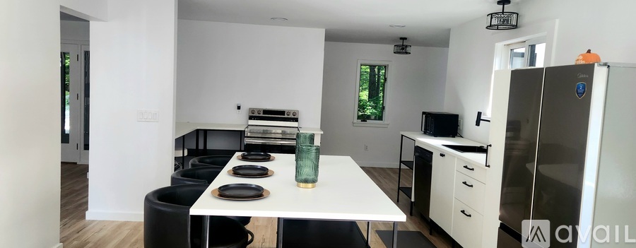 A kitchen with a white table and black chairs.
