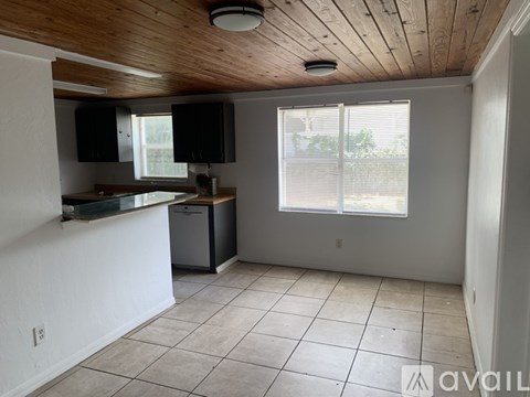 A kitchen with white cabinets and a wooden ceiling.