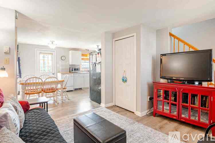 A living room with a couch, a chair, a dining table, a television, and a staircase.