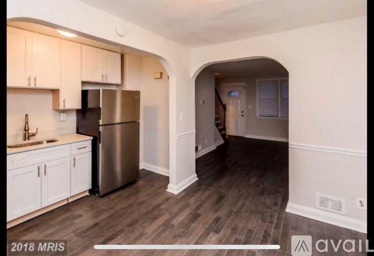 A kitchen with white cabinets and a stainless steel refrigerator.