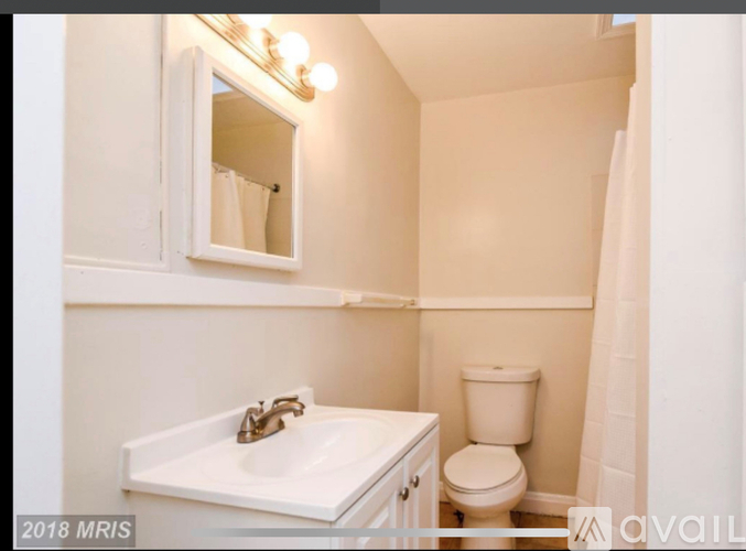 A bathroom with a sink, toilet, and mirror.