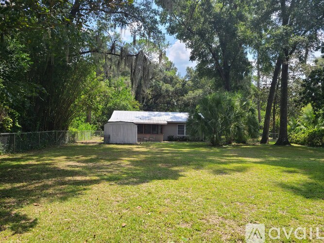 A small house is surrounded by trees in a grassy area.