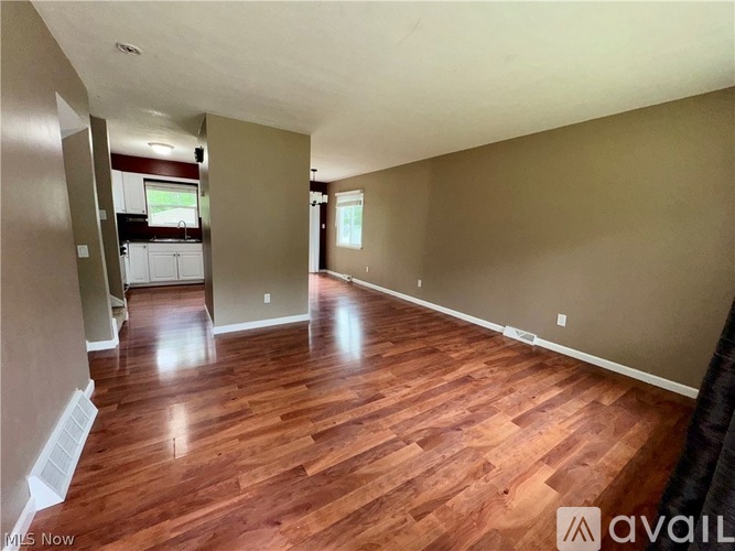 A spacious room with wooden flooring and beige walls.