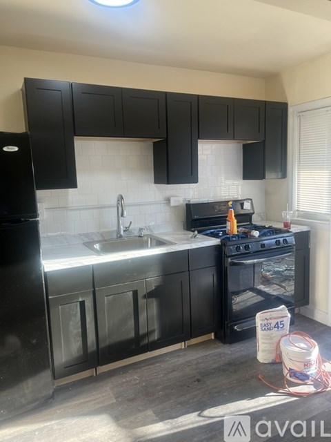 A kitchen with black cabinets and a stove top oven.