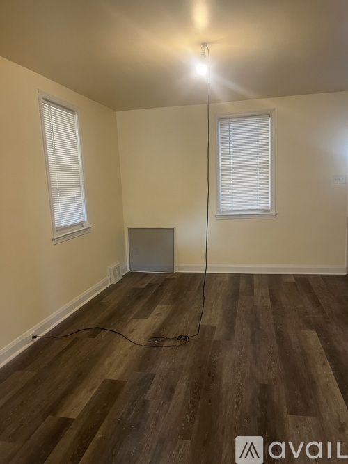 A room with wooden flooring and a window with blinds.