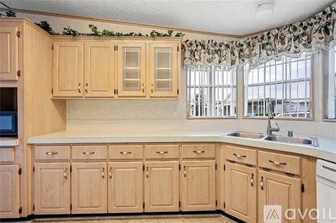 A kitchen with wooden cabinets and a window with a curtain.