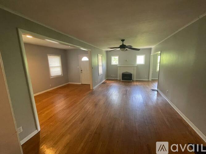 A spacious room with wood flooring and a ceiling fan.