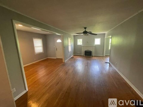 A spacious room with wood flooring and a ceiling fan.