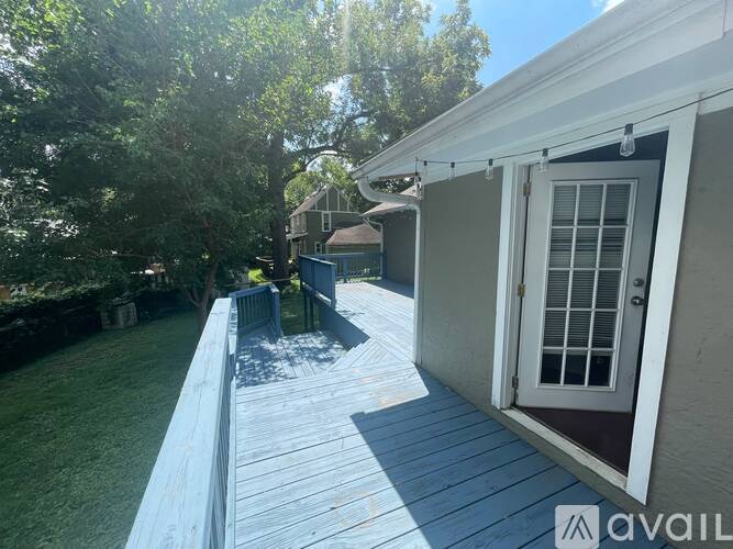 A wooden deck leads to a house with a white door.