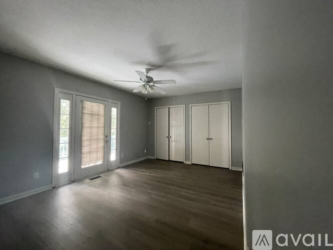 A room with a ceiling fan and sliding glass doors.