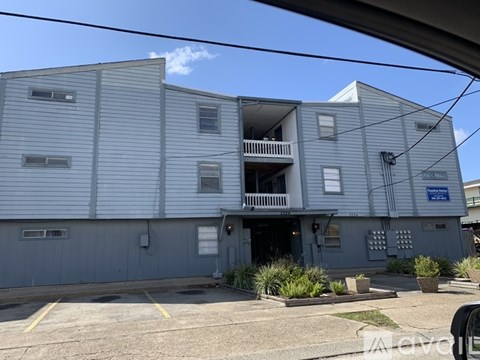 A grey apartment building with a blue sign on the right side.