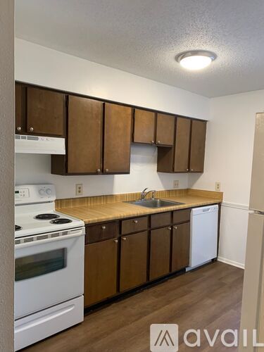 A kitchen with white appliances and wooden cabinets.