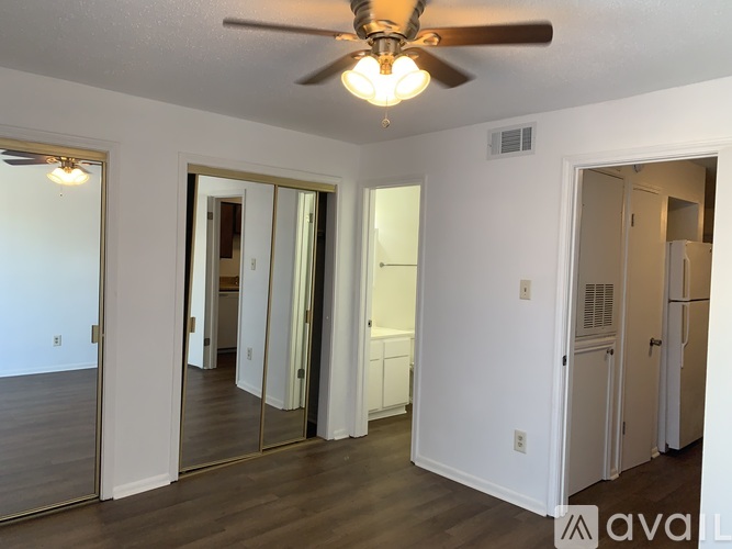 A room with a ceiling fan and sliding glass doors.