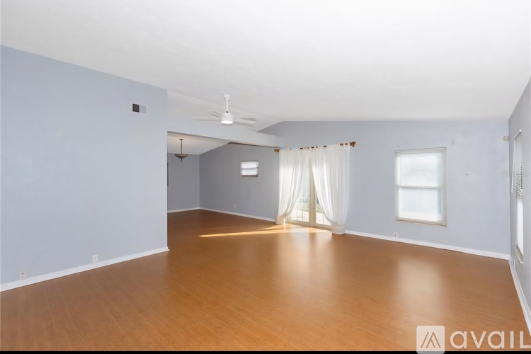 A spacious room with wooden floors and white walls.
