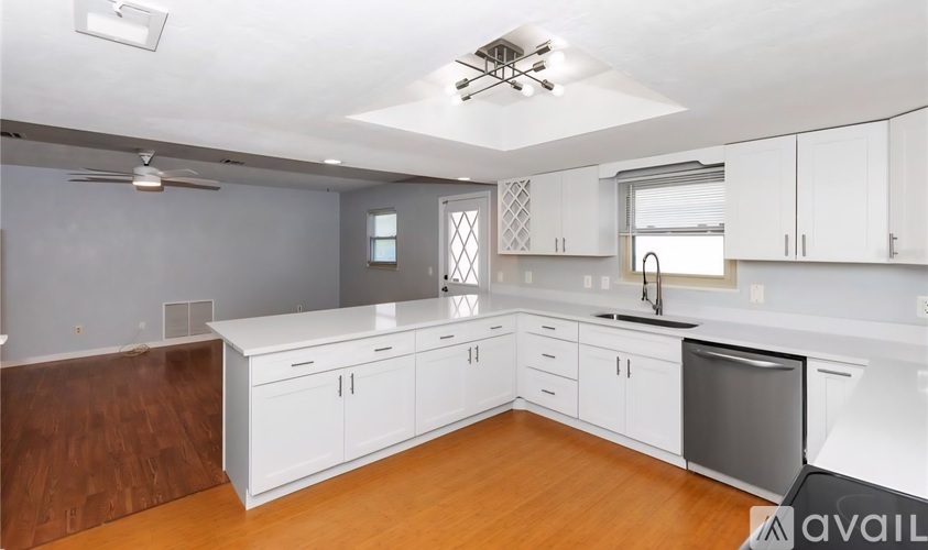 A kitchen with white cabinets and a wooden floor.