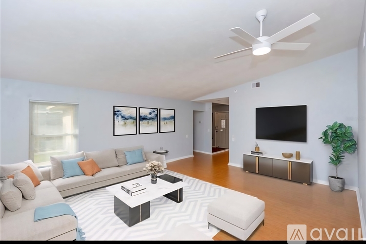 A living room with a white couch, a coffee table, and a television.