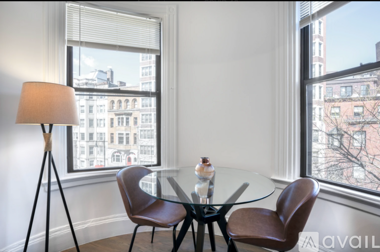 A table with two chairs and a floor lamp in front of a window.