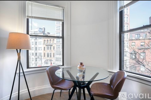 A table with two chairs and a floor lamp in front of a window.