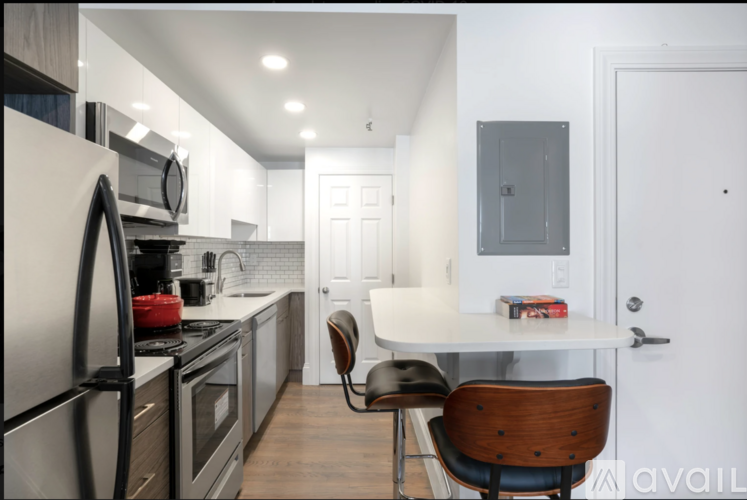 A kitchen with a refrigerator, oven, and a dining table with a chair.