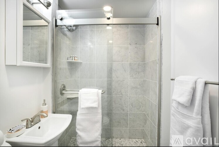 A bathroom with a white sink and a glass shower stall.