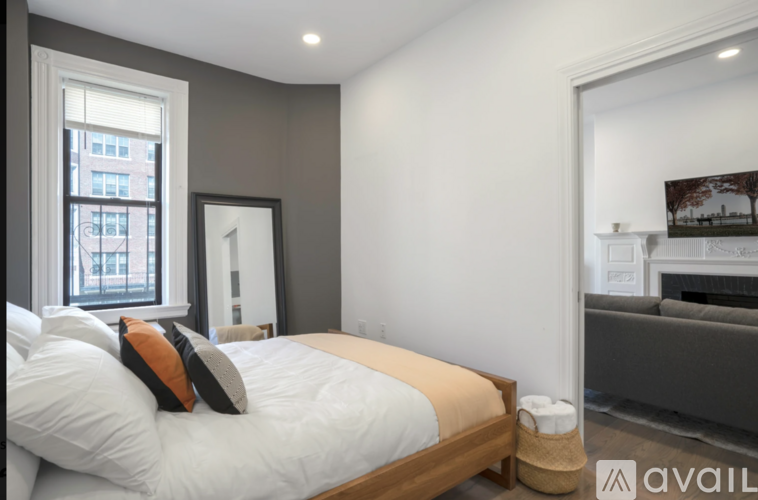 A bedroom with a bed, a couch, and a window.