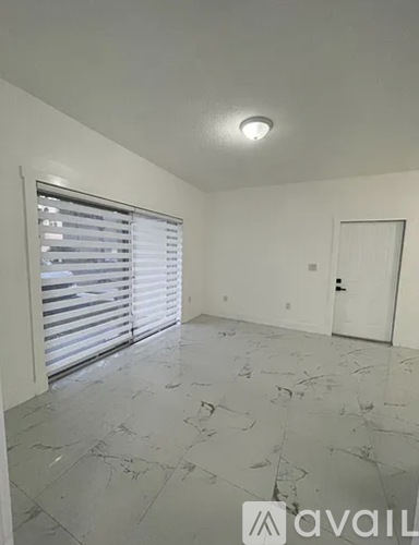 A room with a marble floor and a window with blinds.