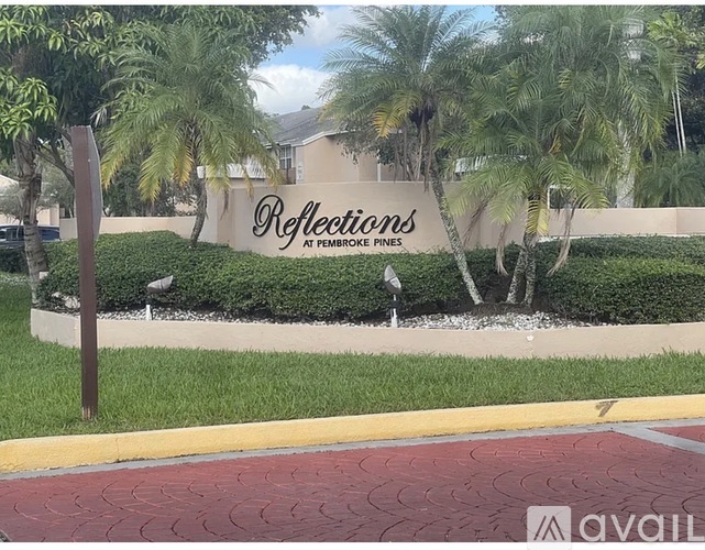 A sign that says "Reflections at Pembroke Pines" is in front of some trees.