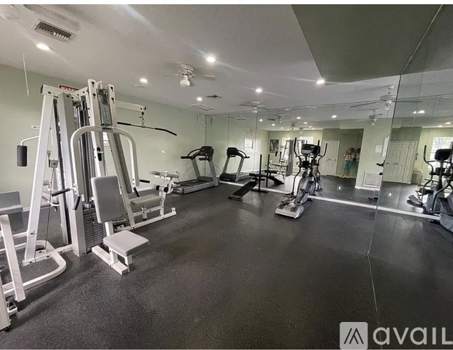 A gym with a variety of equipment including treadmills, weights, and exercise machines.
