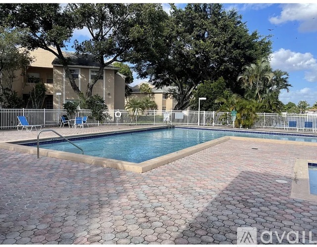 A pool surrounded by a brick patio and trees.